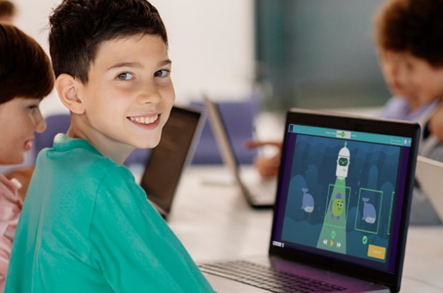 Aluno em frente ao notebook estudando IA para oceanos – uma ferramenta desenvolvida pela Code.org. Ao seu redor, estão a professora e colegas.